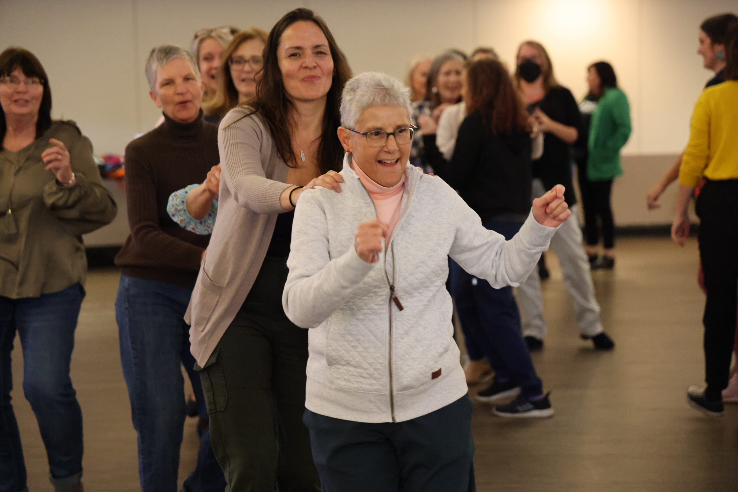 Women joyfully participate in a conga line during a community event