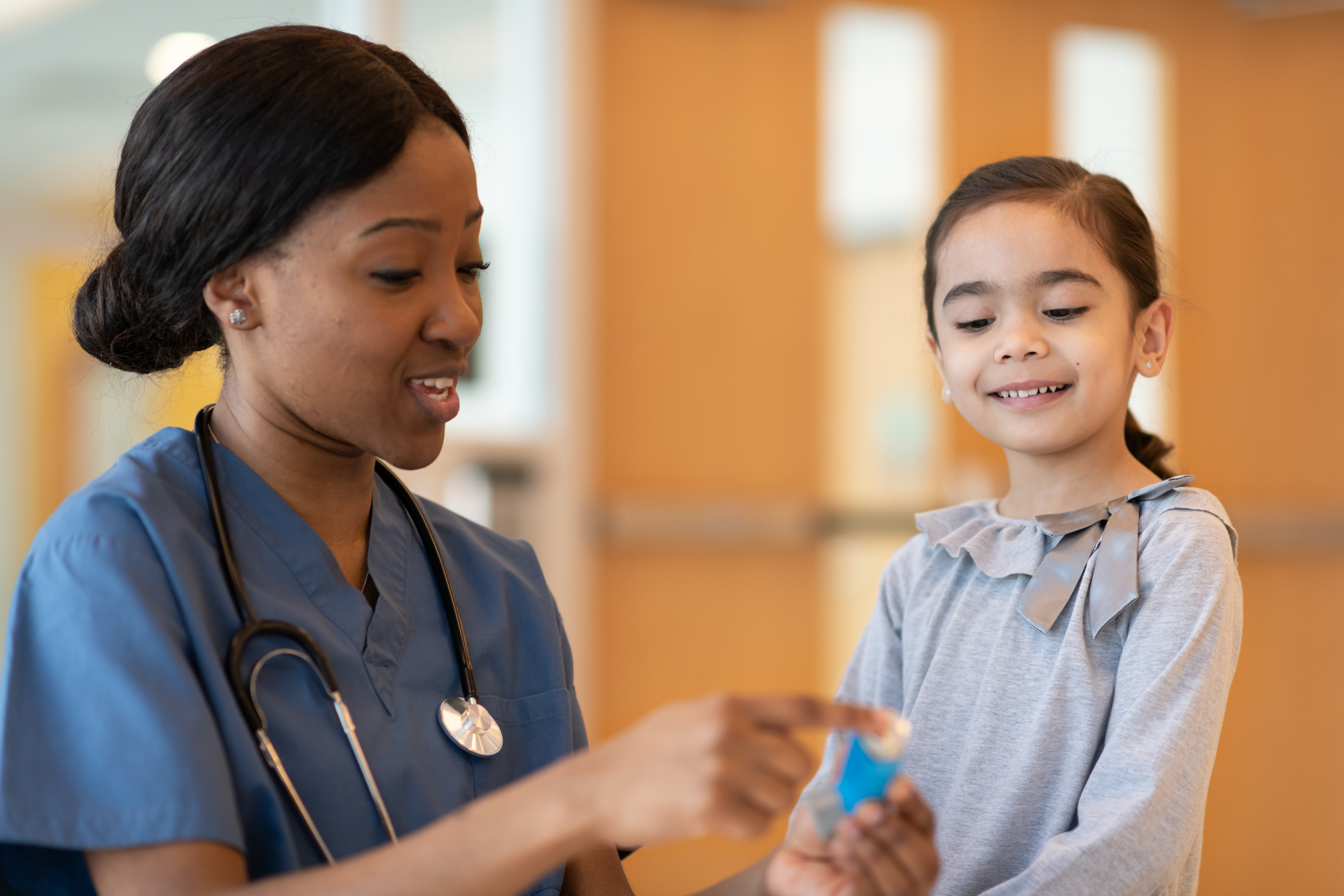 Nurse explaining medication to a smiling young girl in a clinic.