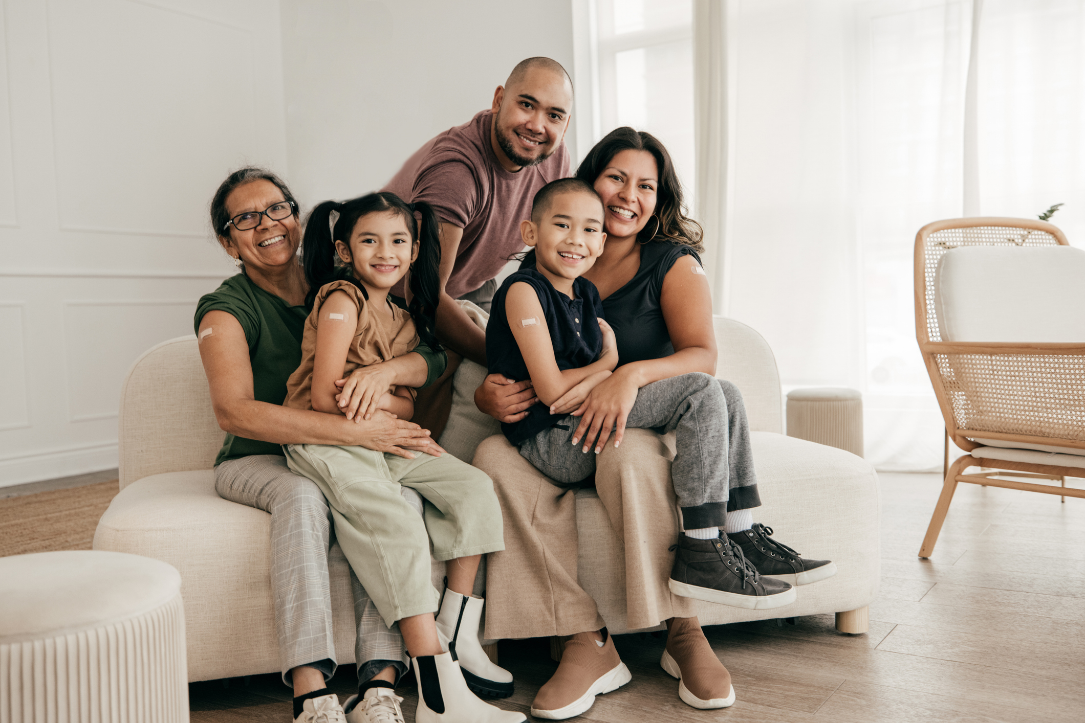 Smiling family sitting on sofa with bandages on their arms