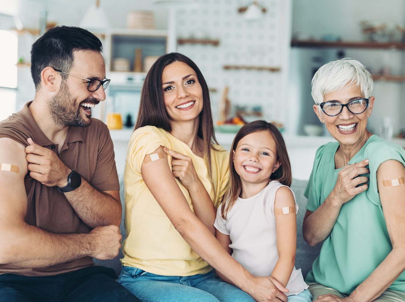 Family smiling with bandages on arms, showing vaccination courage.