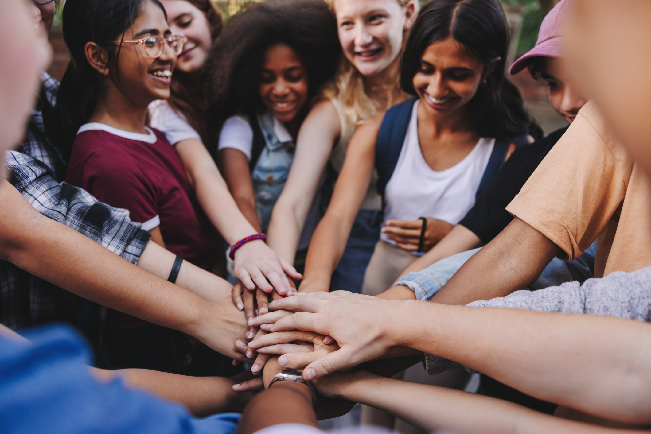 Photo of a group of students in a circle stacking their hands together in the middle