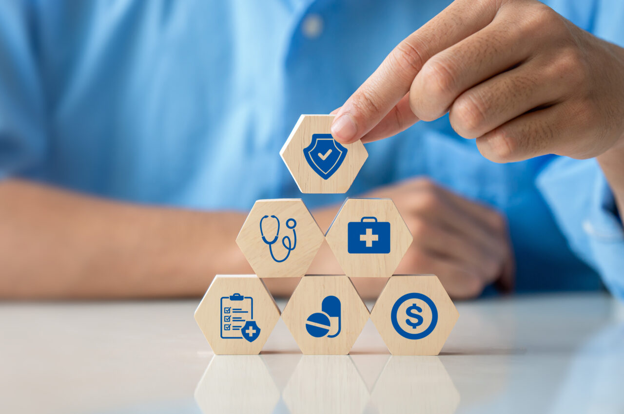 Hand building a pyramid of hexagonal blocks with healthcare icons