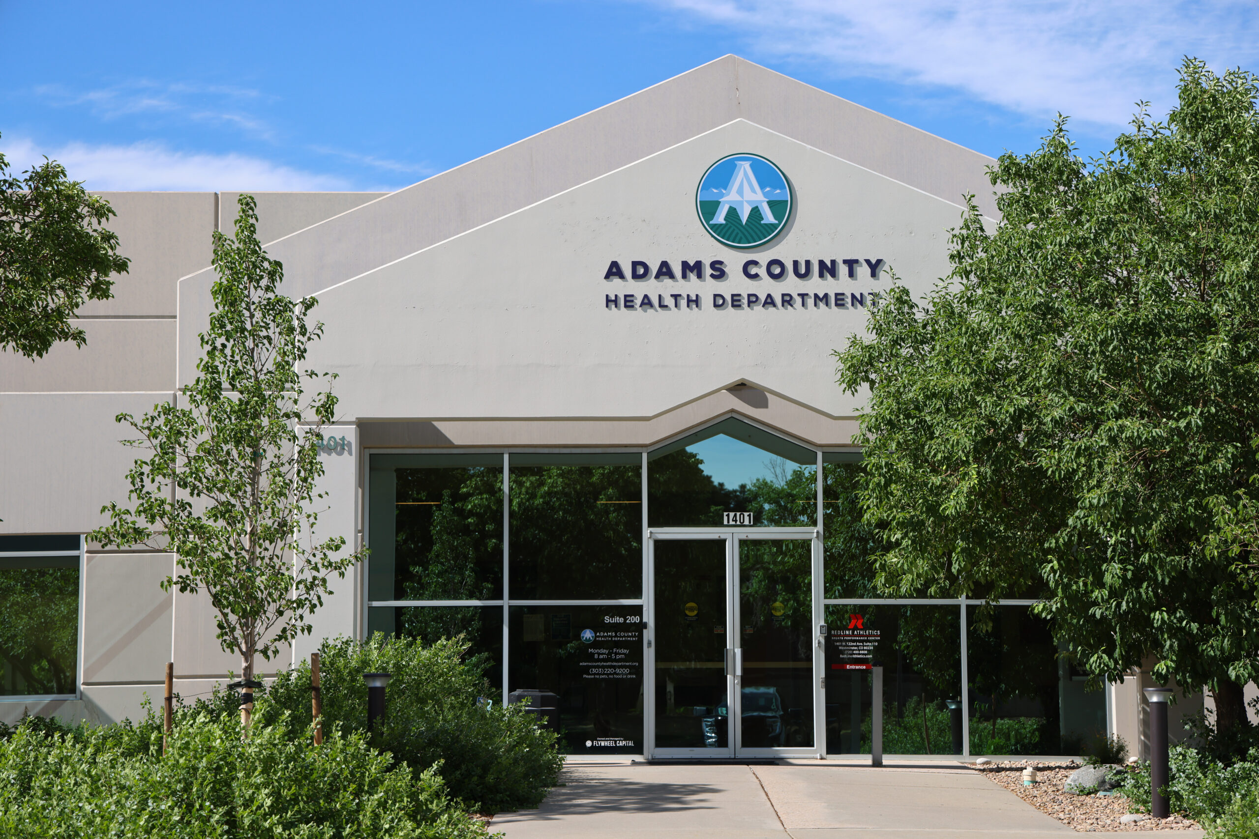 Adams County Health Department building entrance with trees and clear sky