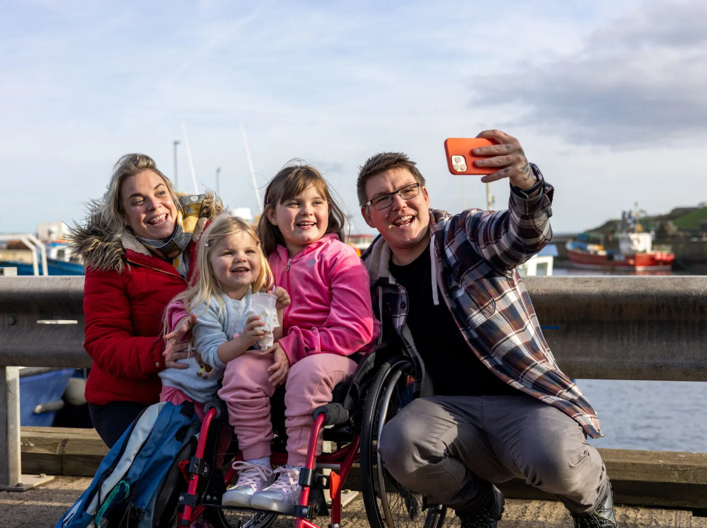 Photo of a family of four taking a photo near a harbor