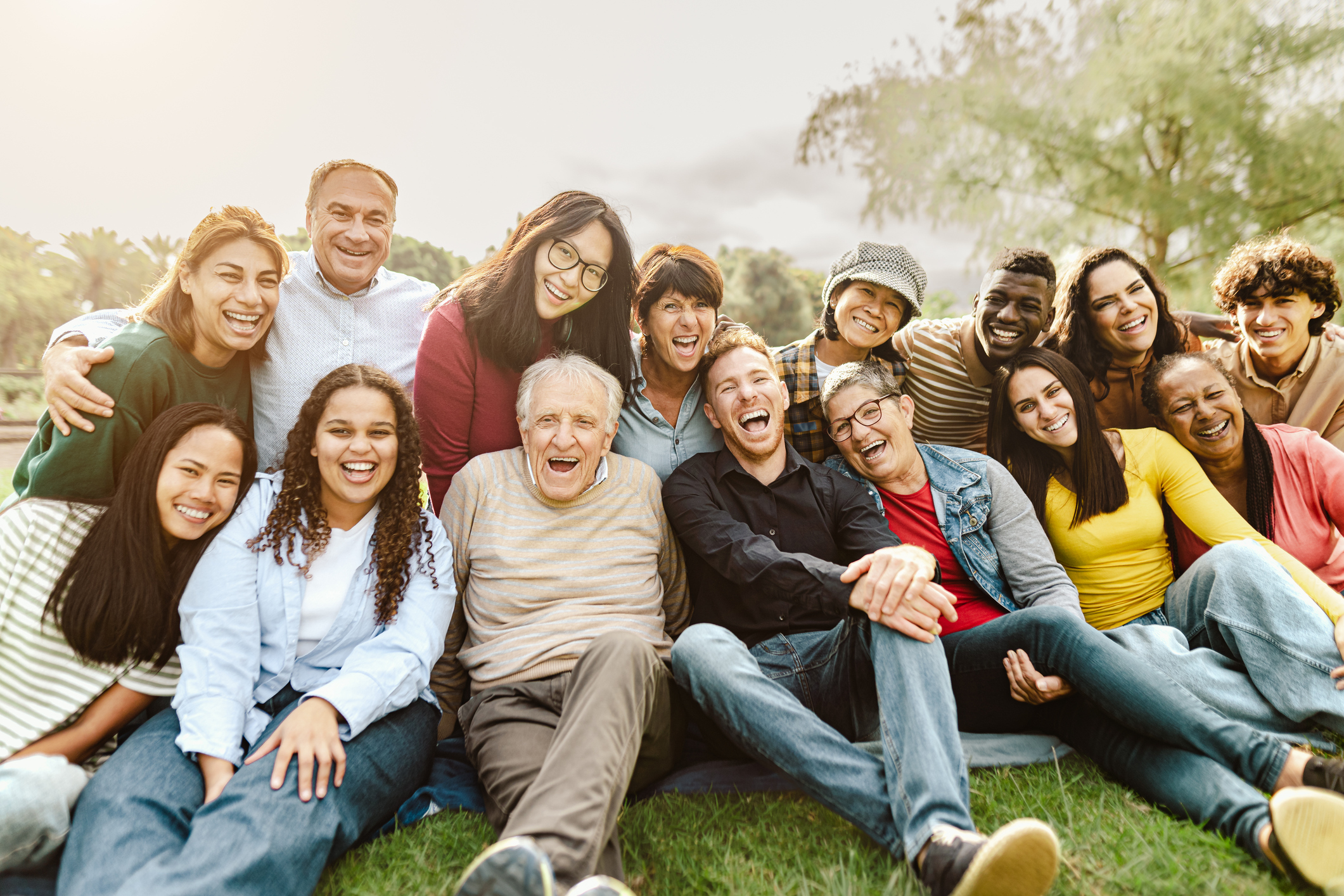 Photo of a large group of people showing people of all ages and backgrounds sitting together, smiling