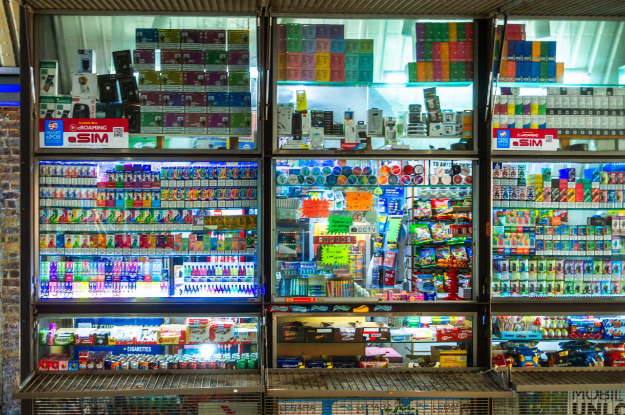 Storefront displaying numerous SIM cards, mobile accessories, and miscellaneous items under bright lights