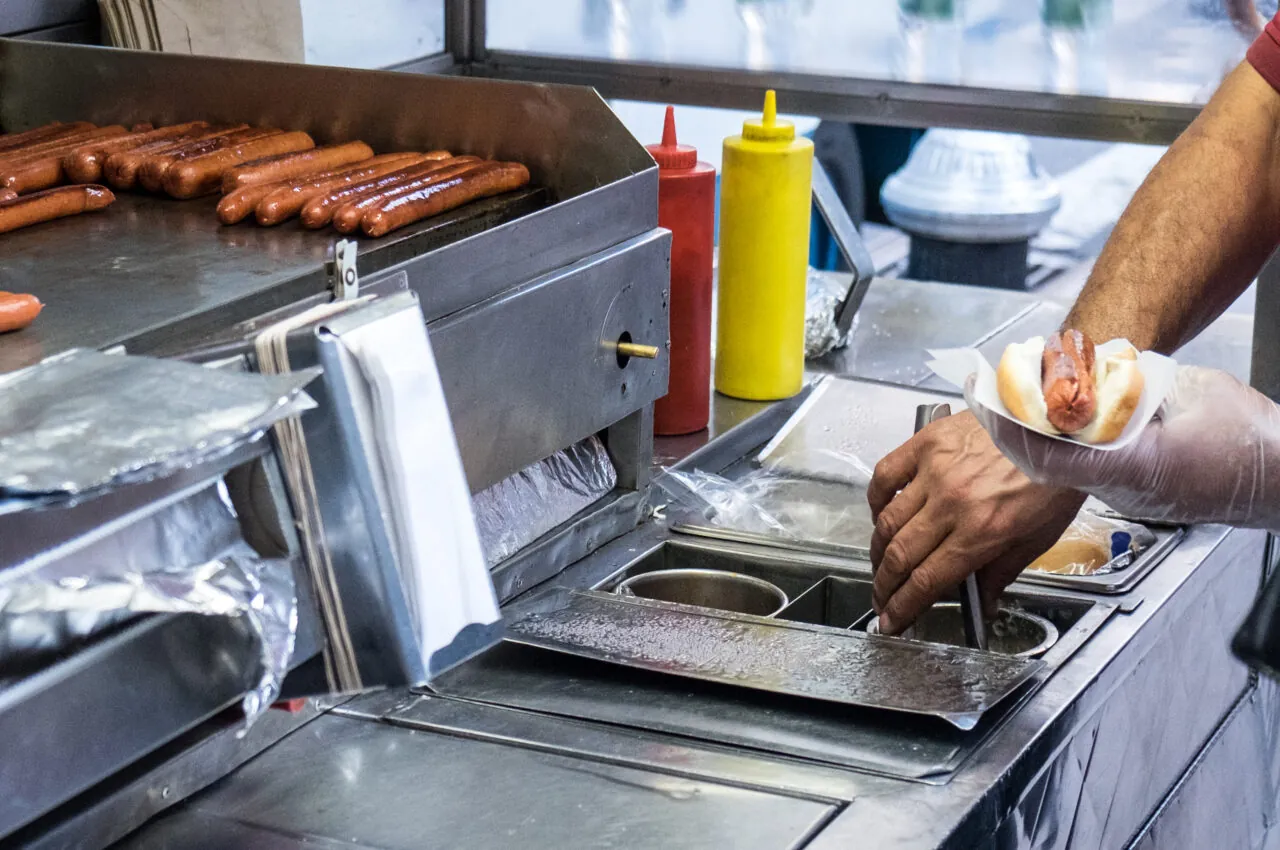 Photo of a push card vendor preparing a hot dog