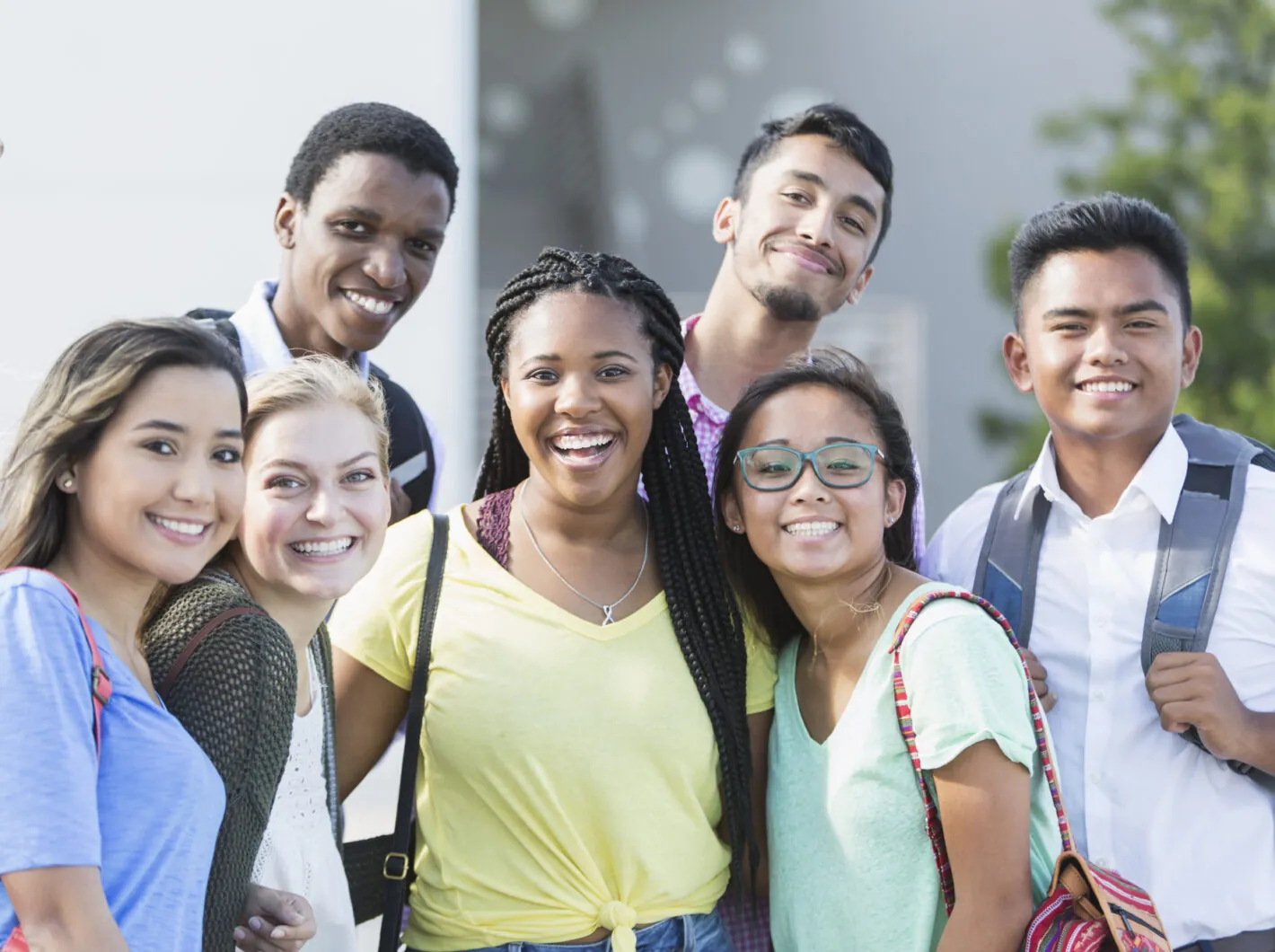 Diverse group of smiling young adults standing together outdoors.