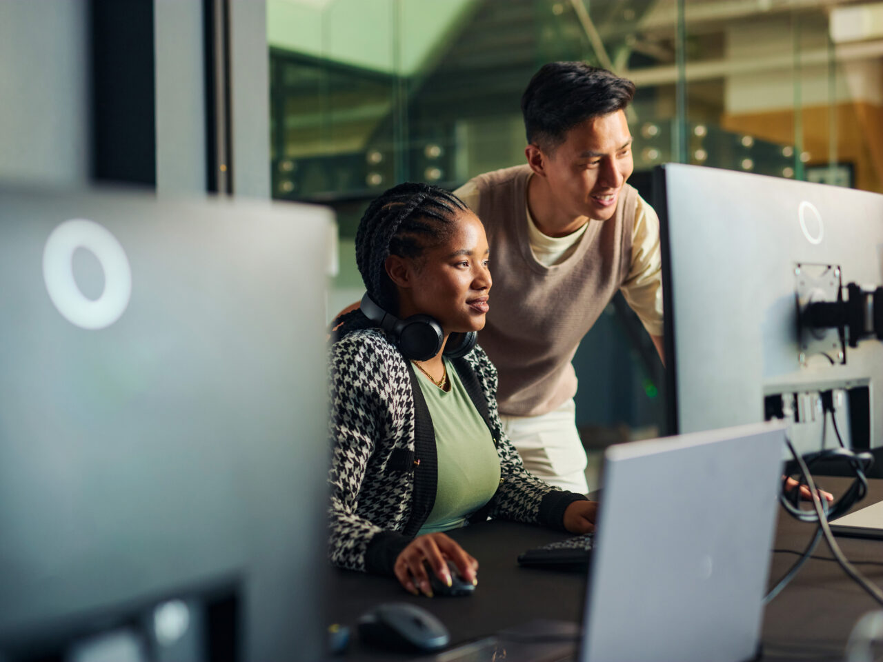 Two people sit in front of a computer smiling