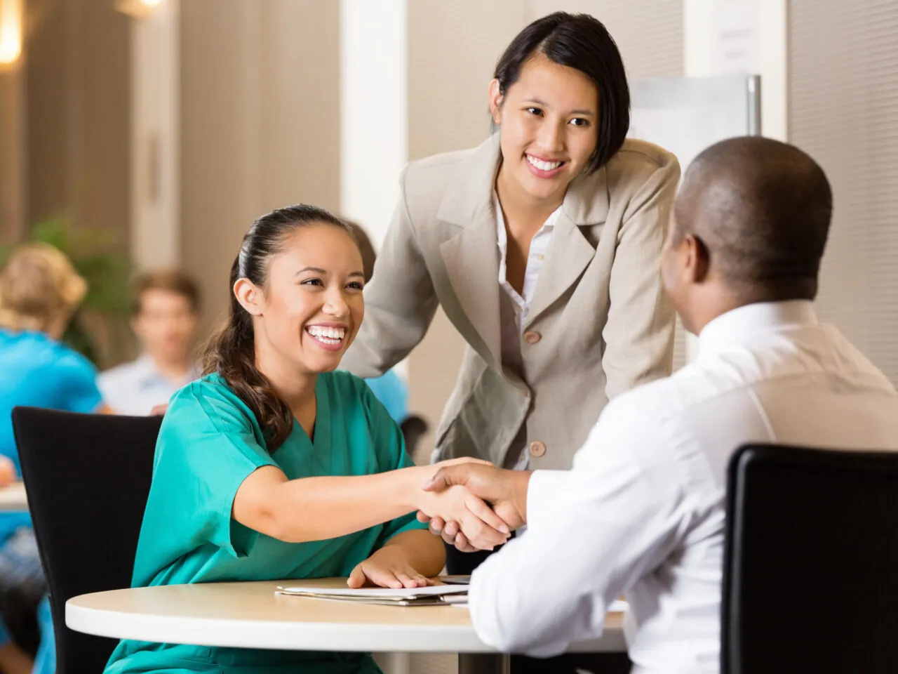 Health care worker shakes hands with a man while a woman in a suit observes