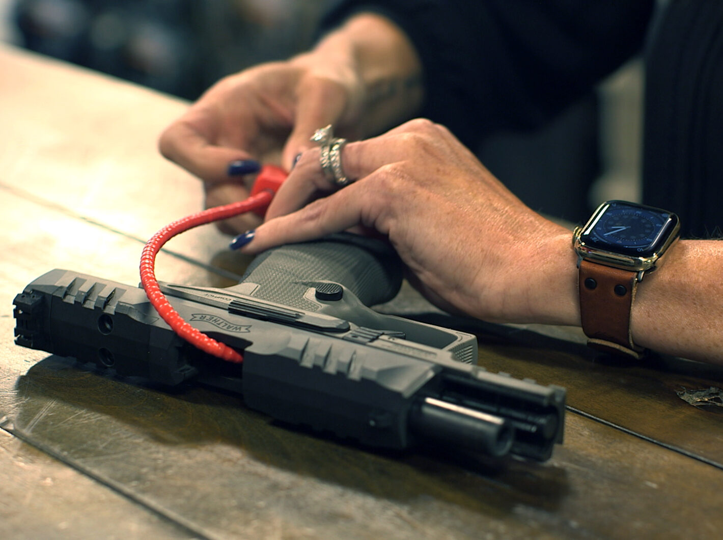 Hands securing a cable lock through a handgun, emphasizing gun safety.