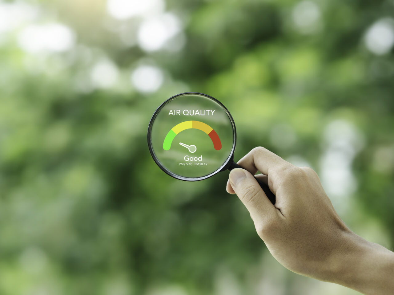 Hand holding a magnifying glass with a depiction of the Air Quality Index on it