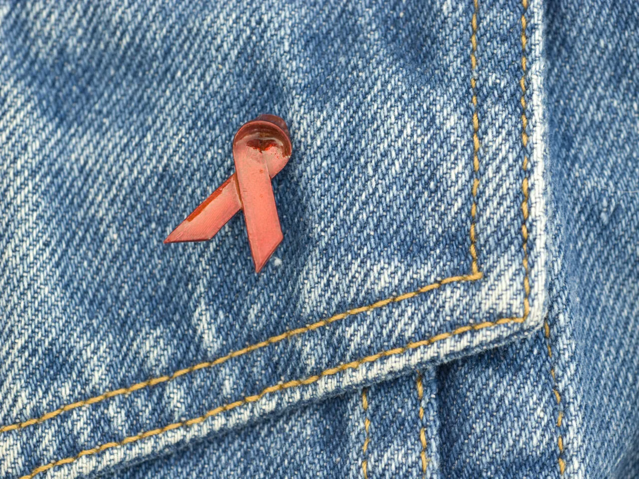 Photo of a red HIV awareness ribbon on blue jeans