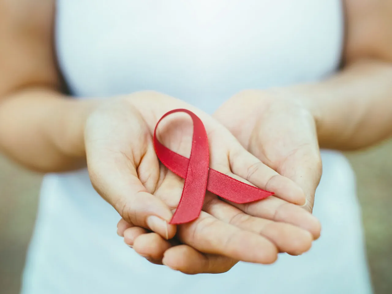 Photo of hands holding a red ribbon symbolizing HIV awareness