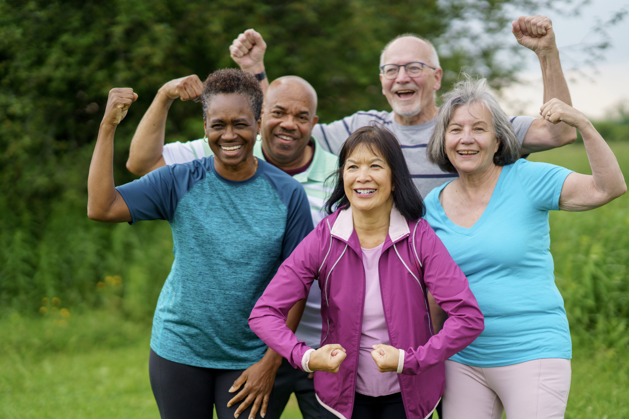 Group of five seniors smiling and flexing arms outdoors